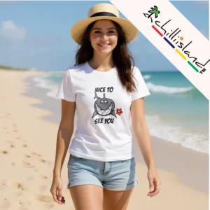 Woman smiling on a sunny beach, wearing a straw hat and a white Chilliisland t-shirt with a cartoon shark and "Nice to See You" text. Chillisland vibe.